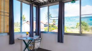 Sabina Guesthouse في شاطئ كامالا: طاولة وكراسي في غرفة بها نوافذ