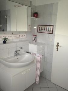 a white bathroom with a sink and a mirror at Ferienwohnung Ruwald in Bad Zwischenahn