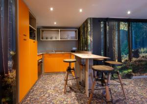 une cuisine orange avec deux tabourets et un comptoir dans l'établissement Hotel Base Camp Lodge - Bourg Saint Maurice, à Bourg-Saint-Maurice