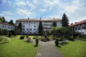 uma pessoa sentada num banco em frente a um edifício em Hotel Monttis em Sucha Beskidzka