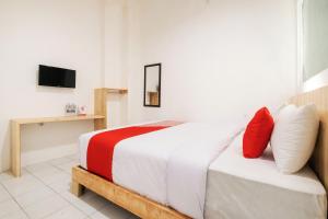 um quarto com uma cama com almofadas vermelhas e brancas em OYO 2041 Griya Aneka em Yogyakarta