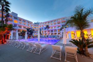 a hotel with chairs and a swimming pool at night at Limanaki Beach Hotel & Suites in Ayia Napa