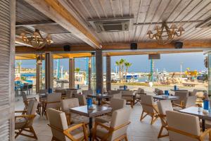 a restaurant with tables and chairs and a view of the ocean at Limanaki Beach Hotel & Suites in Ayia Napa