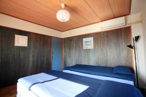 1 dormitorio con 1 cama y pared de madera en 一棟貸しの海宿 Kamakura SUN&BREEZE, en Kamakura