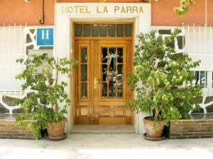 une porte en bois menant à un hôtel la paraza avec deux plantes dans l'établissement Hotel La Parra, à Archena