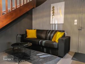 a black leather couch with yellow pillows in a living room at Appartement Le 146 Bis, avec Parking in Rennes