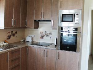 a kitchen with wooden cabinets and a microwave oven at Panorama Beach House, 5 meters to the sea in Pervolia