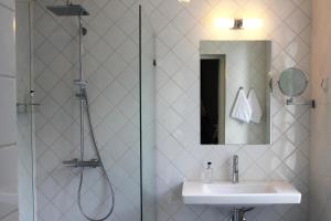 uma casa de banho com um chuveiro, um lavatório e um espelho. em Hotelli Kartanon Meijeri em Mäntsälä