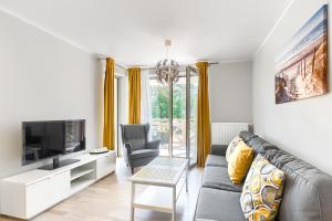 a living room with a couch and a tv at Apartament Bursztynowy Rezydencja Park in Mielno