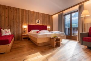 a bedroom with a bed and a couch and a window at Saltria - your Alpine experience in Alpe di Siusi