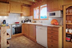 a kitchen with wooden cabinets and a white dishwasher at Chalet Tekoa - OVO Network in Manigod