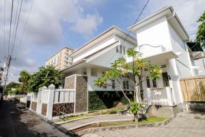 uma casa branca com uma árvore em frente em Palem Kipas Homestay em Yogyakarta