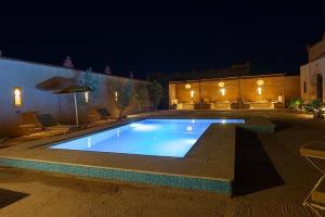 a large swimming pool in a yard at night at Riad Ouzine Merzouga in Merzouga