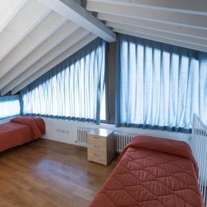 a bedroom with two beds and large windows at Nido del Tadini in Lovere