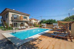 a swimming pool with chairs and a house at Sophia's Beach House in Levktron