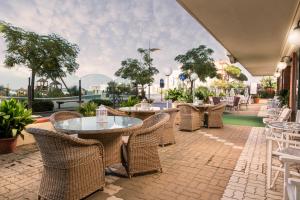 a patio with wicker tables and chairs with a view at Hotel Ambasciatori Beach Front Breakfast e Brunch XXL fino alle 12 30 in Misano Adriatico