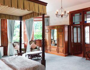 a bedroom with a canopy bed and two chairs at Tinakilly Country House Hotel in Rathnew