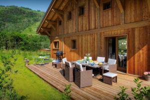 a house with a wooden deck with a table and chairs at Chalet Pajules - OVO Network in Le Fey