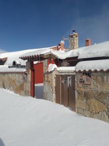 un edificio cubierto de nieve con un cartel. en CASA RURAL GREDOS, en San Martín de la Vega del Alberche