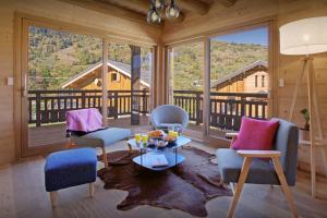 a living room with chairs and a table and large windows at Chalet Pajules - OVO Network in Le Fey