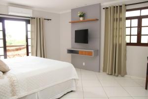 a white bedroom with a bed and a tv at Casa Pedra Bonita in Rio de Janeiro