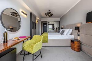 a room with a bed, chair and a mirror at Hotel Omorika in Crikvenica