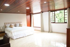 a bedroom with a white bed and large windows at Casa Pedra Bonita in Rio de Janeiro