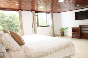 a bedroom with a white bed with a television on the wall at Casa Pedra Bonita in Rio de Janeiro
