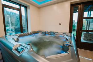 a jacuzzi tub in a room with windows at Mountain Paradise & Wellness in Izvoare