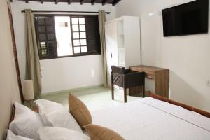 a bedroom with a bed and a desk and a television at Casa Pedra Bonita in Rio de Janeiro