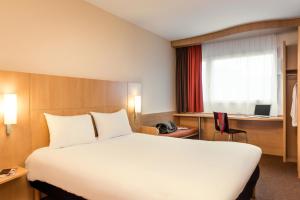 um quarto de hotel com uma cama grande e uma secretária em ibis Charleville Mézières em Villers-Semeuse