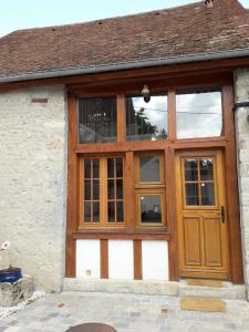 a large wooden door on a building with windows at Maison en pierre totalement renovée in Marsainvilliers