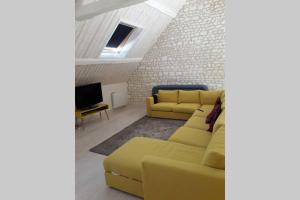 a living room with a yellow couch and a tv at Maison en pierre totalement renovée in Marsainvilliers
