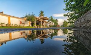 un riflesso di una casa in un corpo idrico di Heritage Resort Hampi a Hampi