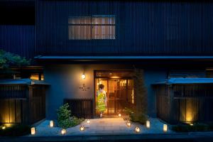 una mujer de pie fuera de una casa por la noche en THE JUNEI HOTEL Kyoto Imperial Palace West, en Kioto