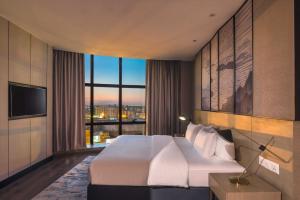 a hotel room with a bed and a large window at Aber Unayzah in Unayzah