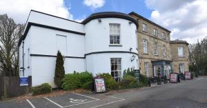 a white building with a black roof on a street at The Mount by Greene King Inns in Wigan