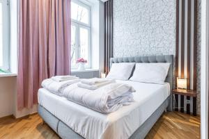 a bedroom with a large bed with white sheets at ZEUS Design Apartments in Vienna