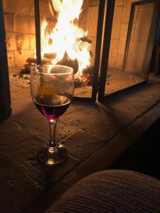 a glass of wine sitting in front of a fireplace at Hospedaria Pertim do Céu in São Francisco Xavier