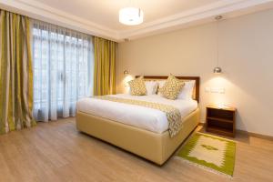 ein Schlafzimmer mit einem Bett und einem großen Fenster in der Unterkunft Cozy Residences by Trianum in Nairobi