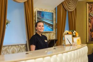 Eine Frau, die hinter einem Tisch in einem Zimmer steht. in der Unterkunft Catherine Art Hotel in Sankt Petersburg