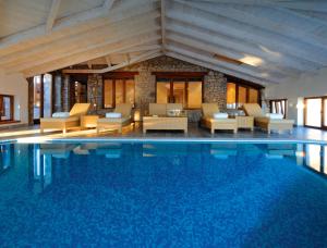a large swimming pool in a building with furniture at Santa Marina Arachova Resort & Spa in Arachova