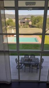 a table and chairs on a porch with a view of a pool at suites del champaqui in Villa General Belgrano