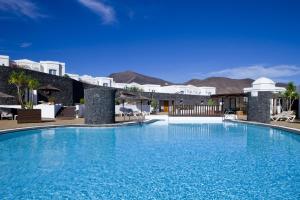 a swimming pool in a resort with mountains in the background at Apartamentos LIVVO Coloradamar in Playa Blanca