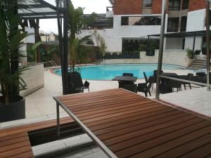 a patio with a wooden table and a swimming pool at Longonot Place Serviced Apartments in Nairobi
