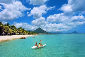 two people on surfboards in the water on a beach at Luxor appartement in Flic-en-Flac