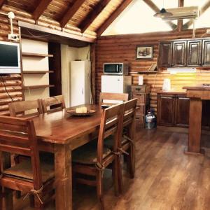 cocina con mesa de madera con sillas y nevera en La Posada en Villa Ventana