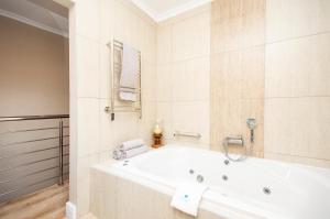 een witte badkamer met een bad en een wastafel bij Nautilus Guesthouse in Port Elizabeth +110 foto's