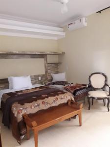 a bedroom with two beds and a chair at Hotel Avenida in Pardinho