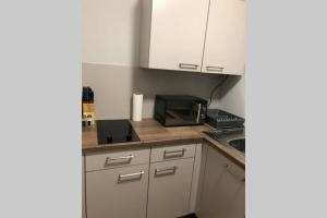 a small kitchen with white cabinets and a microwave at Liverpool · CHILLINGHOUSE # 8, ICE 3 Min. NETFLIX in Siegburg